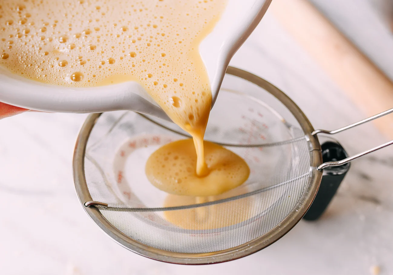 Straining custard through a fine mesh strainer